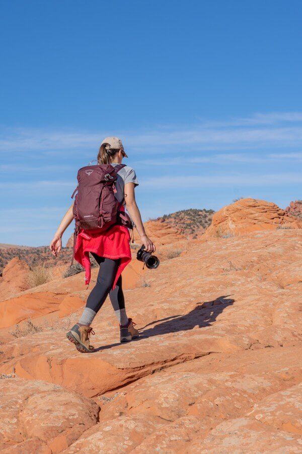 Hiker with camera on red orange sandy rocks on a bright blue day