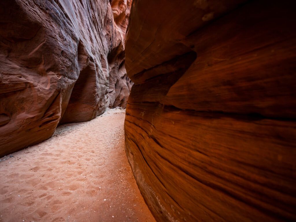 Slot canyon with red walls and sandy trail in kanab utah