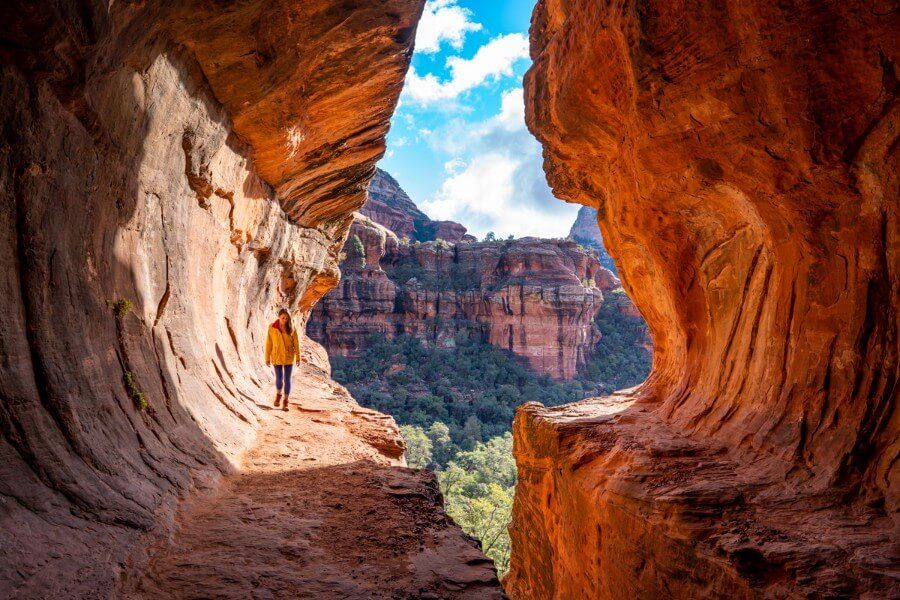 Subway Cave glowing with hiker walking spur trail on the Boynton Canyon hike