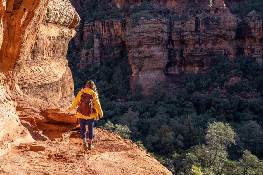 Hiking a narrow ledge path on sandstone rocks to enter subway cave in Sedona Arizona