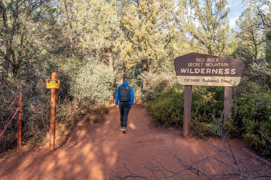 Red Rock Wilderness sign with hiker passing into path