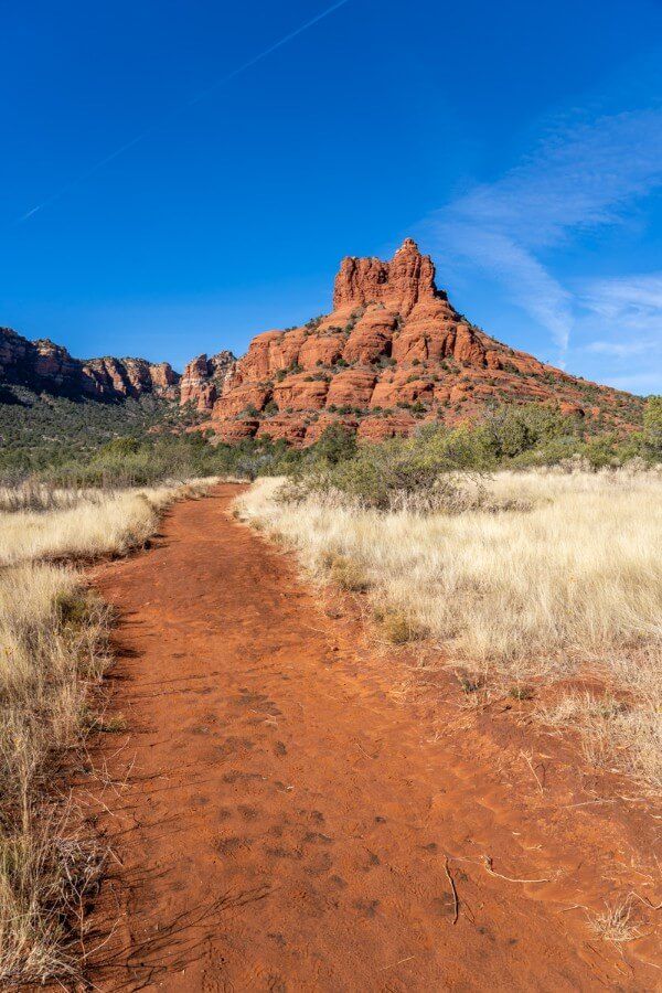 Bell Rock formation at the end of a dirt path surrounded by yellow grass on the courthouse butte loop trail in sedona arizona