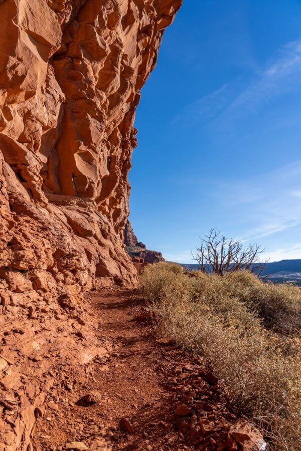 Narrow path hugging an overhanging sandstone wall
