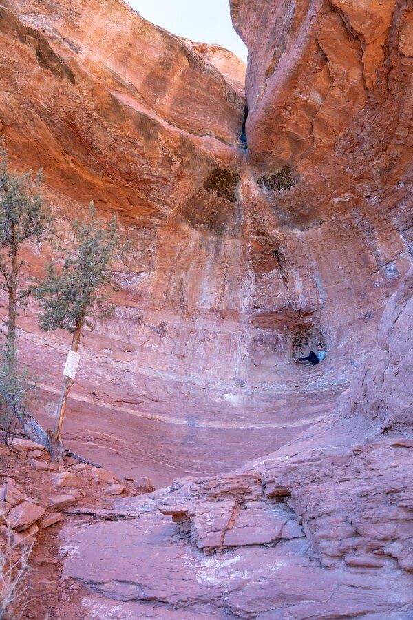 Hiker sat inside a spherical shaped depression in a rock formation