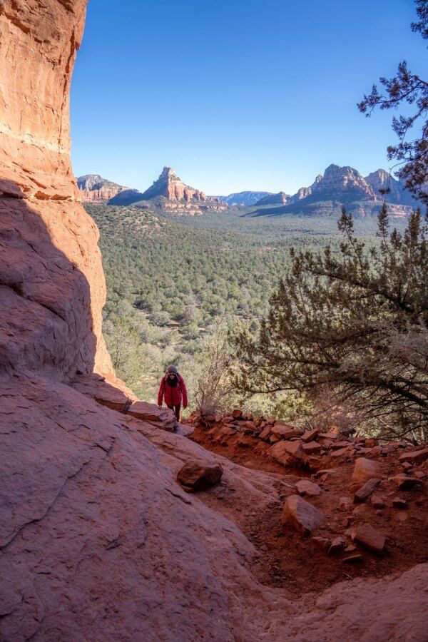 Hiker climbing a steep trail with far reaching views behind