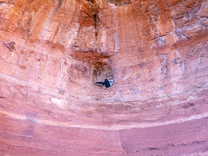 Hiker sat inside sphere shaped hole inside Birthing Cave off Long Canyon Trail in Sedona Arizona how to find and access the cave