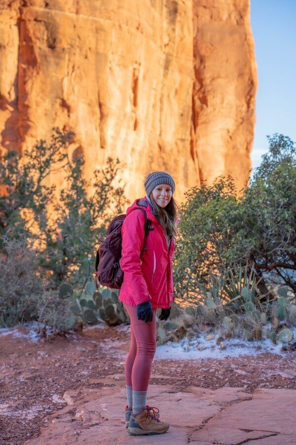 Hiker with pink raincoat and gloves on a sunny morning in winter exploring northern arizona