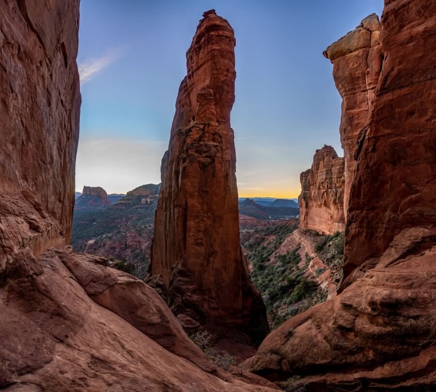 Single rock formation shaped like a sharks fin before sunrise surrounded by red rocks