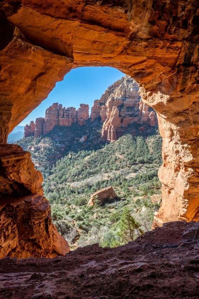 Center of Keyhole Cave in Sedona looking out at red rocks and blue sky