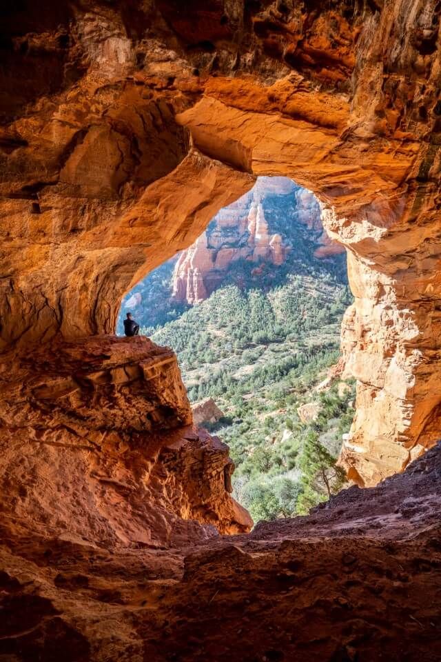 Inside Keyhole Cave Sedona with hiker sat on ledge