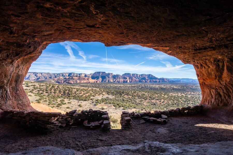 Main window looking out onto landscape with red rocks and trees from inside Hideout Cave at the end of Robbers Roost Trail in Sedona Arizona