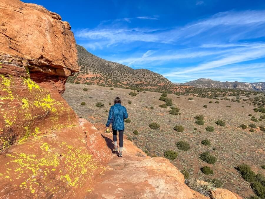 Hiking a rocky ledge with desert background on a sunny day in arizona