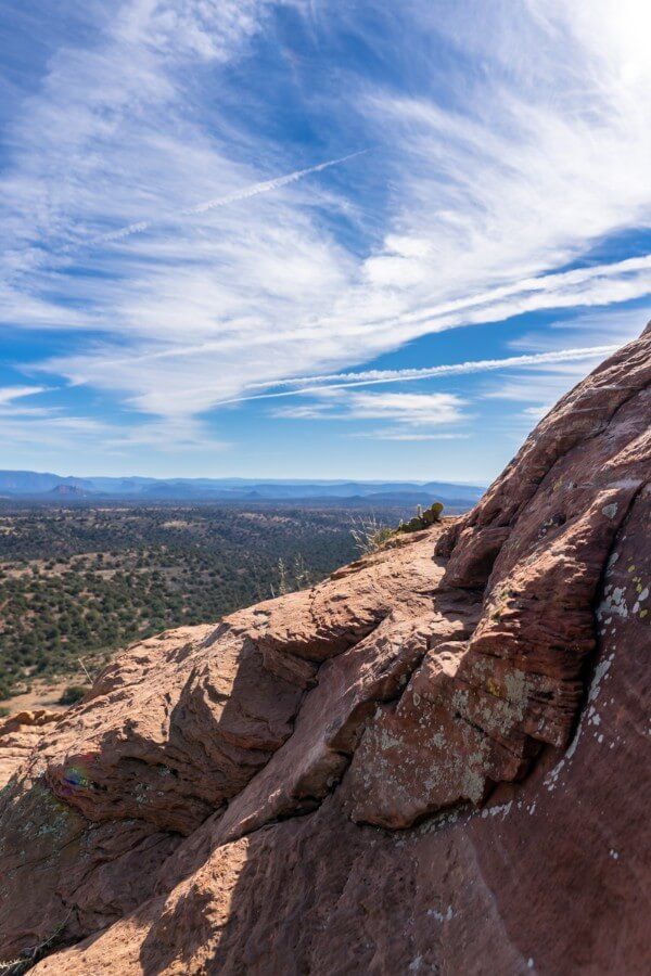 Narrow rocky ledge with blue sky and trees in valley below