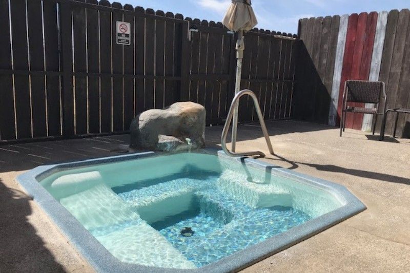 A hot tub at Surprise Valley Hot Spring with fence and umbrella