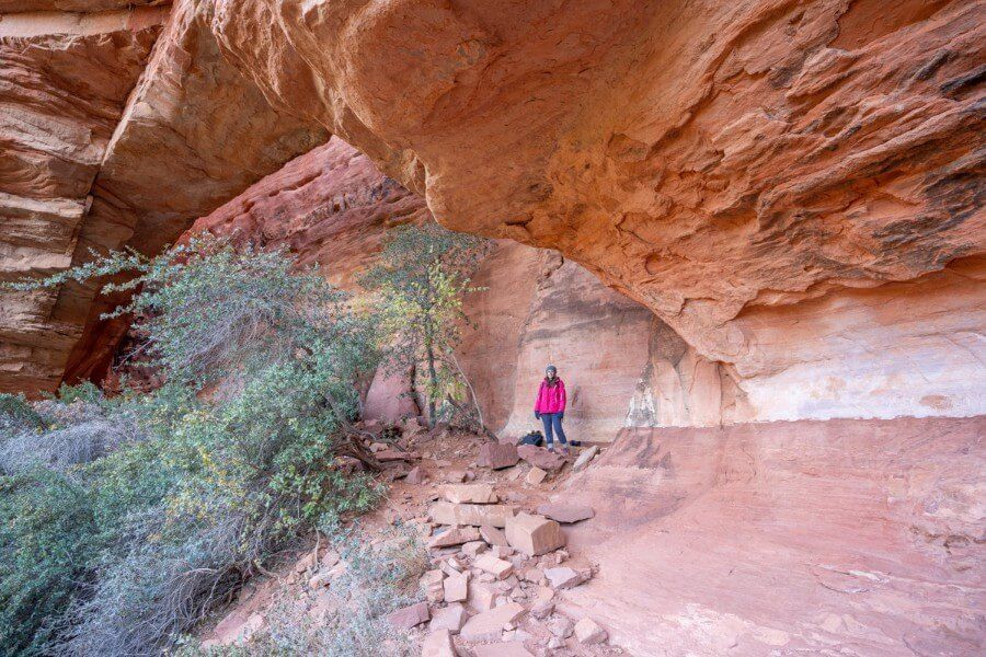 Hiker stood underneath rock formation sandstone rocks and trees