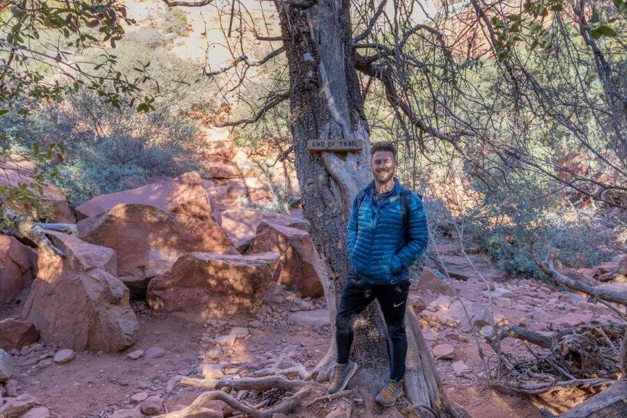 Hiker at end of trail sign on a tree in shadow on the Fay Canyon Trail in Sedona Arizona