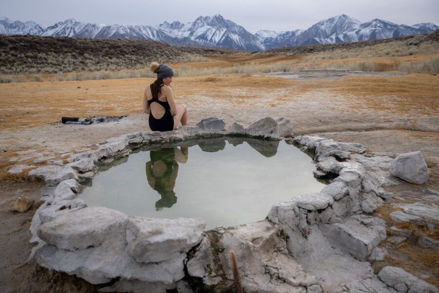Woman sitting on the edge of crab cooker hot spring near Mammoth Lakes in California