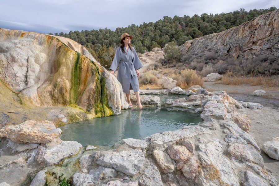 Women in robe with hat dipping toe into a pool