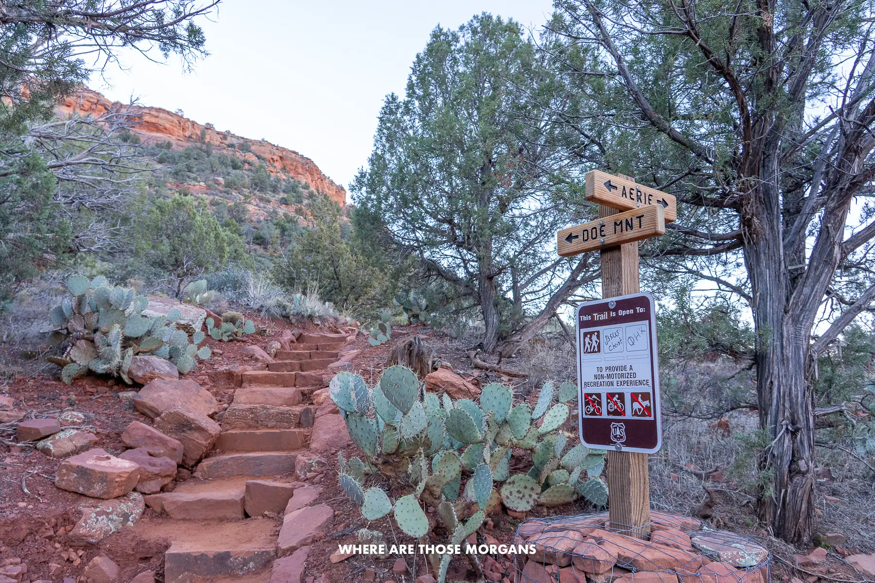 Photo of a connecting point between two hiking trails in a red rock landscape in Arizona with steps leading up a cliff