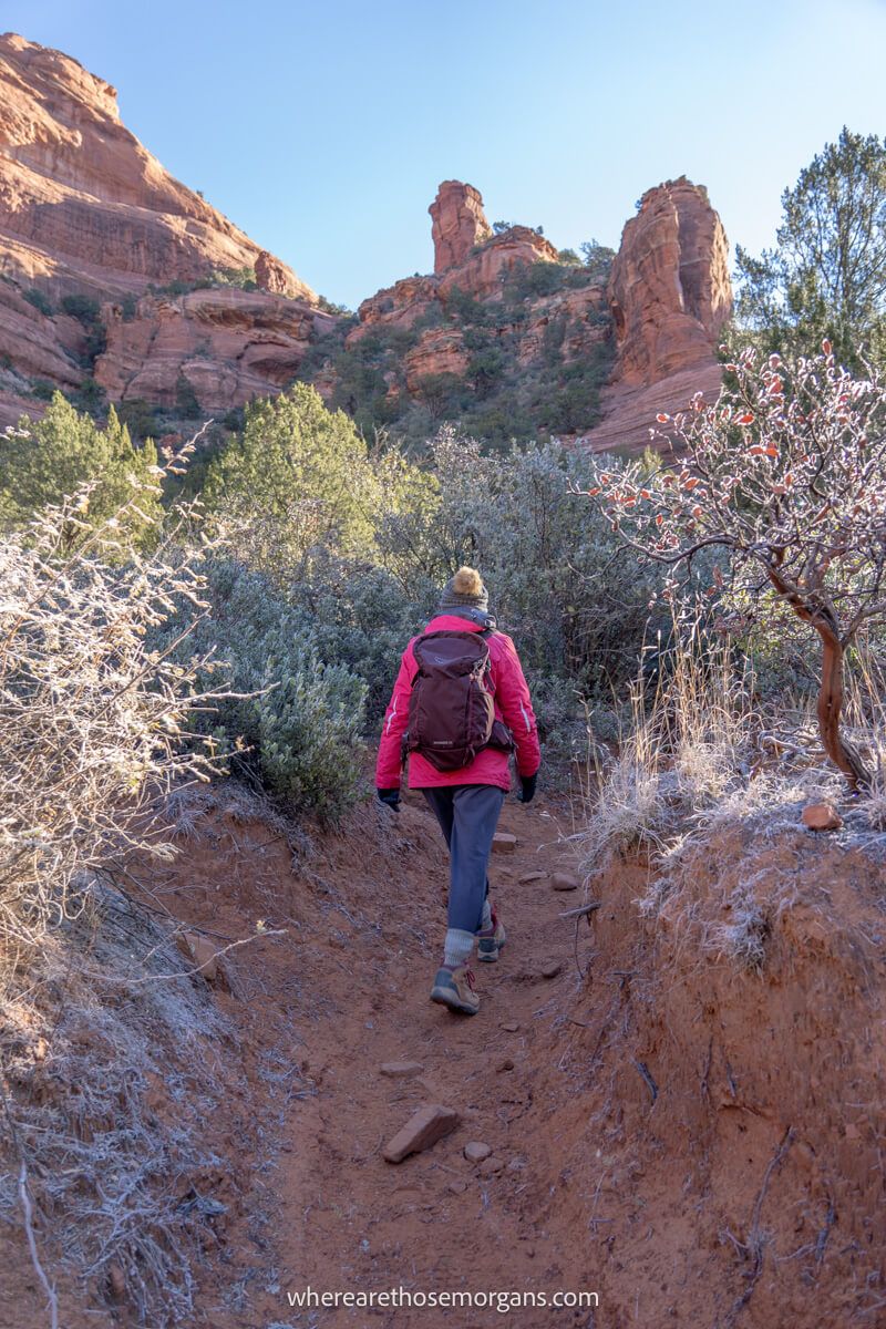 Hiker walking through a dry creek towards red rocks