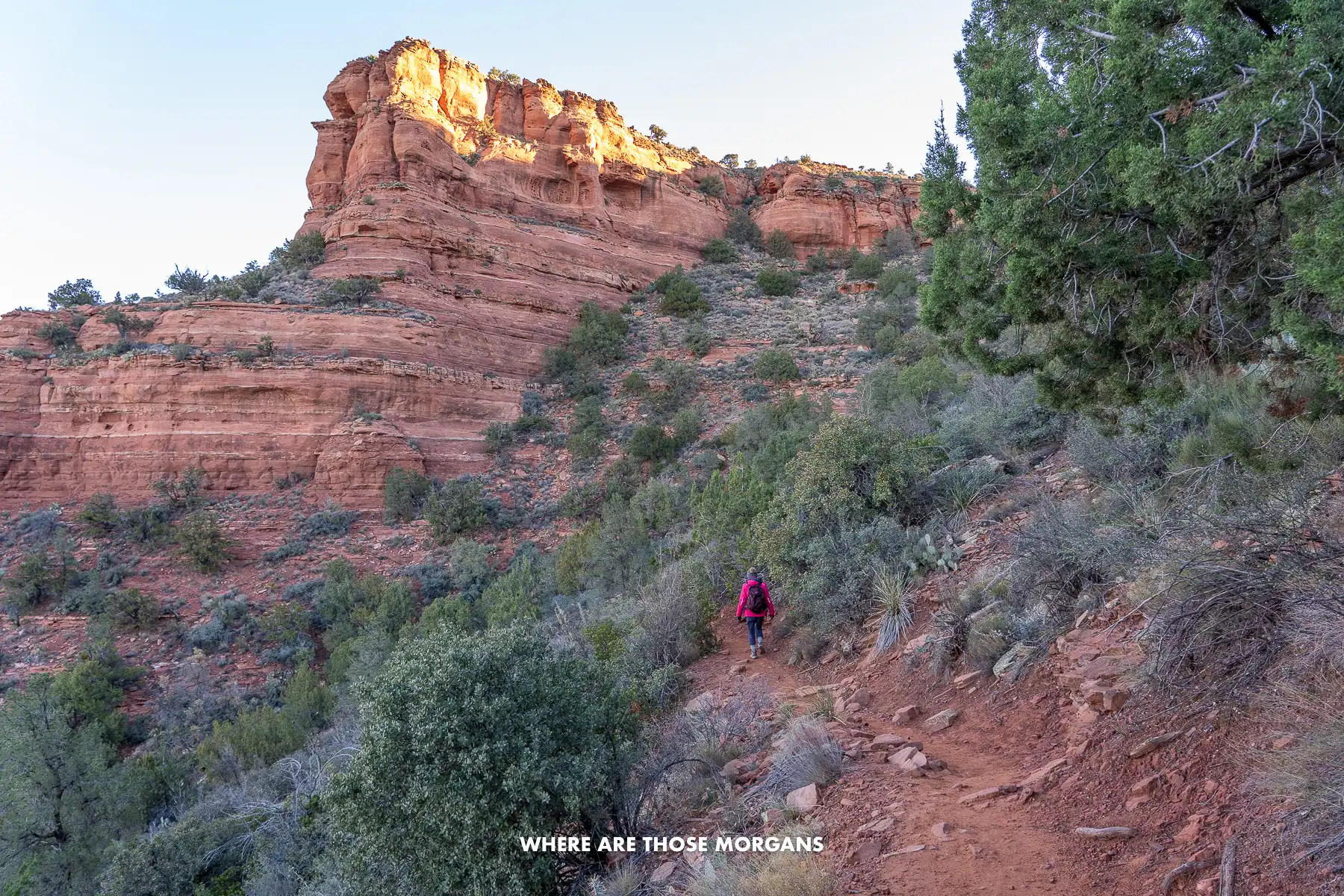 Photo of Kristen from Where Are Those Morgans hiking along a narrow switchback trail on a cliff side in Sedona AZ at dawn