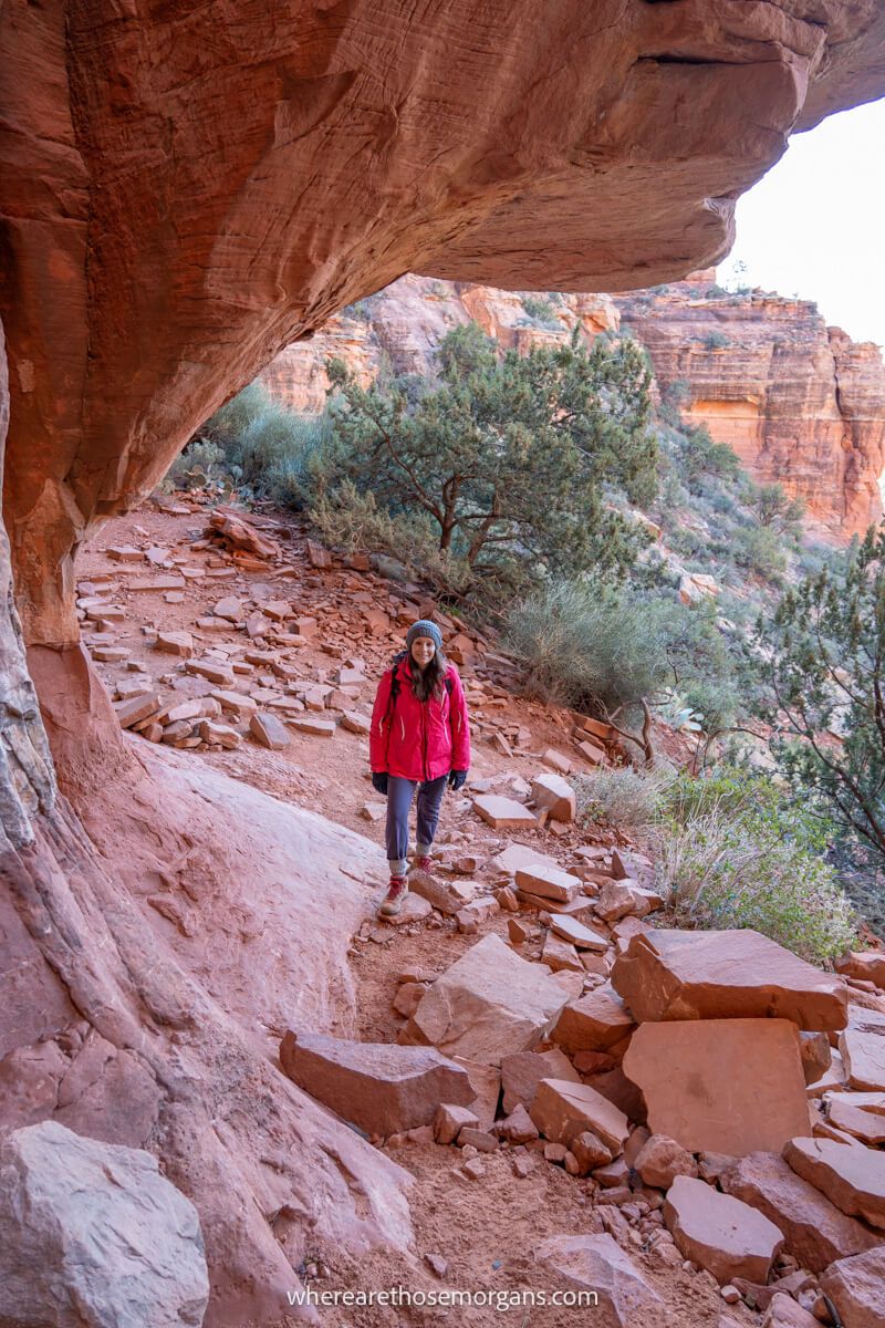 Hiker in winter clothes at the base of Fay Canyon Arch in Sedona surrounded by red rocks