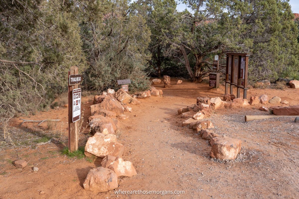 Hiking trailhead with information boards and stones leading to a path