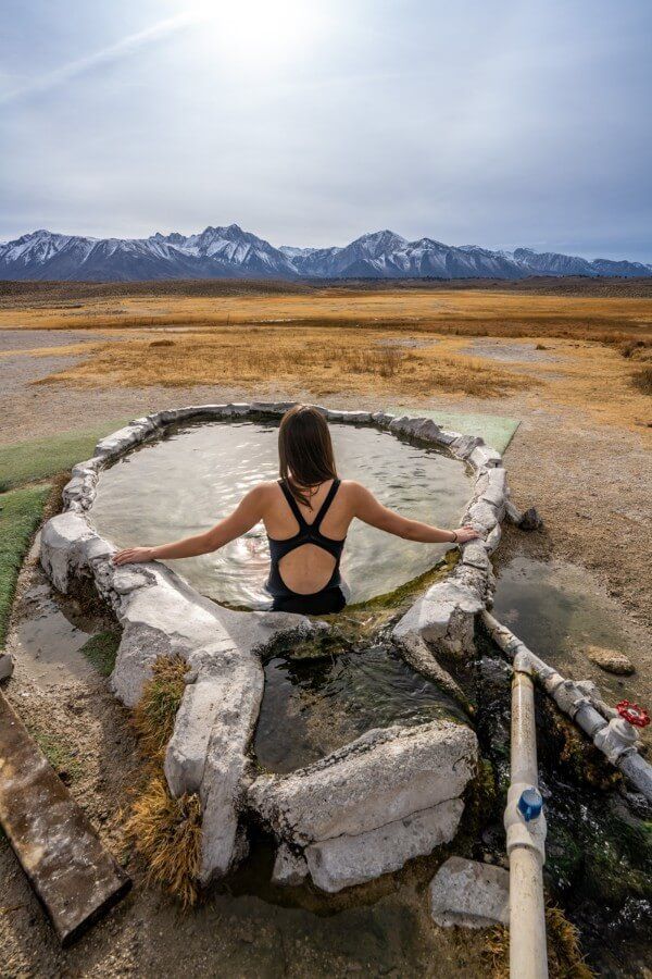 Woman sitting in Hilltop Hot Springs in Mammoth Makes, CA