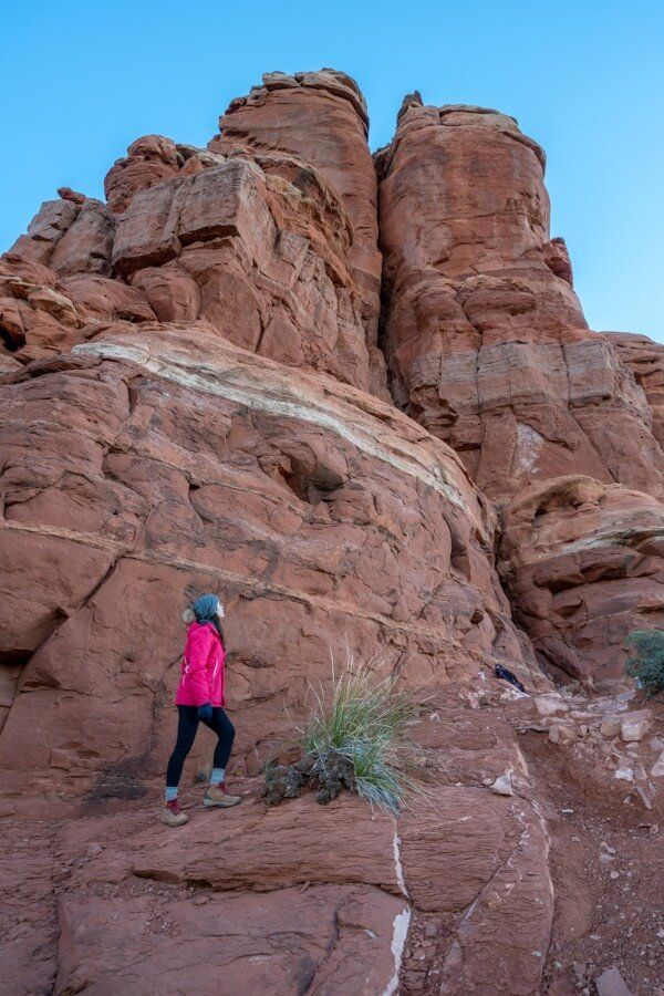 Hiker at the base of Chimney Rock spires in Sedona Arizona at sunrise looking up for perspective