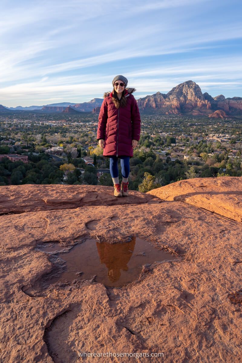 Woman in winter coat at Airport Mesa Vortex Site in Sedona with reflection in puddle