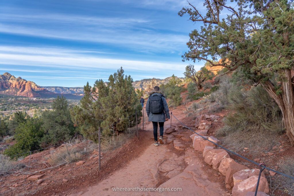 Man hiking on red rocks with winter coat and backpack