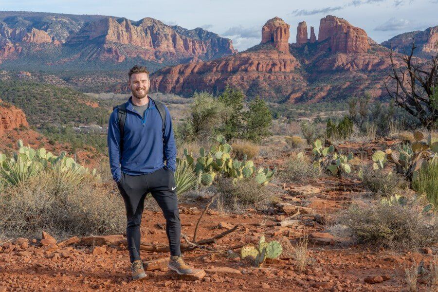 Hiker on a dirt path with red rocks and cacti in arizona