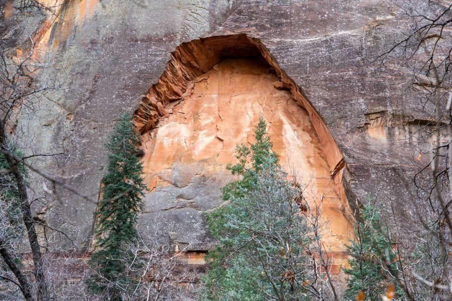 Huge natural arch eroded from a towering rock wall face