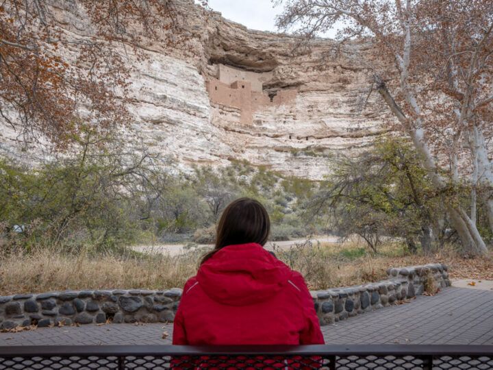 Woman looking at Montezuma Castle from park bench
