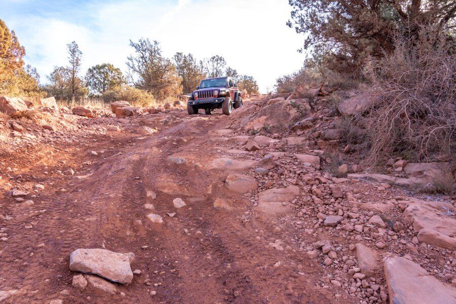 Steep descent into Diamondback Gulch in a maroon Jeep Rubicon in Sedona Arizona