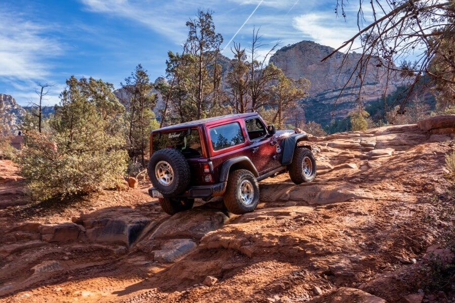 Climbing steep and uneven rocks in a maroon Jeep on the awesome Broken Arrow Trail in Sedona Arizona