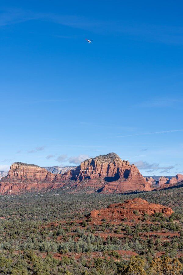 A helicopter high in the air above the red rocks in Sedona