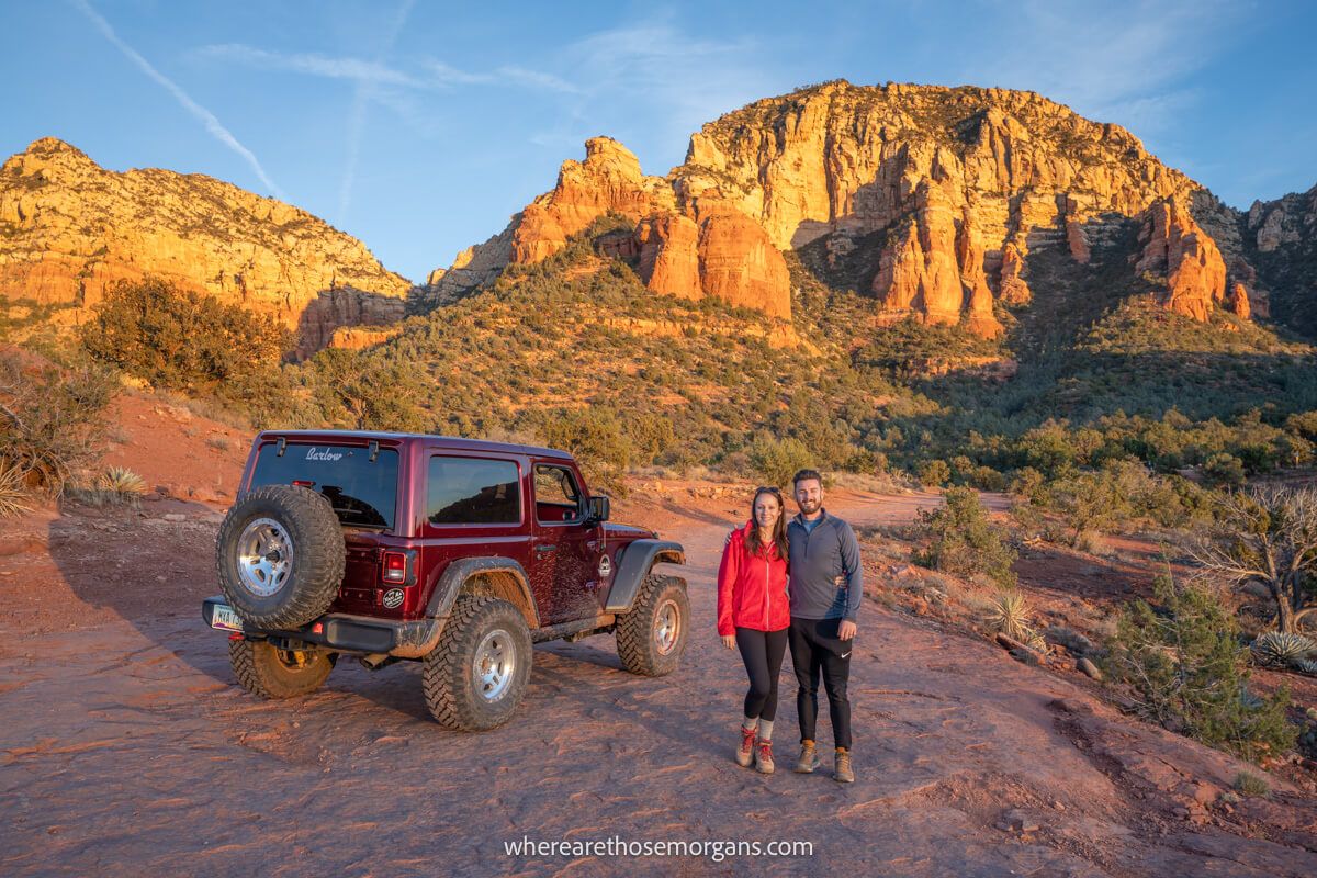couple standing together next to Jeep in Sedona at sunset