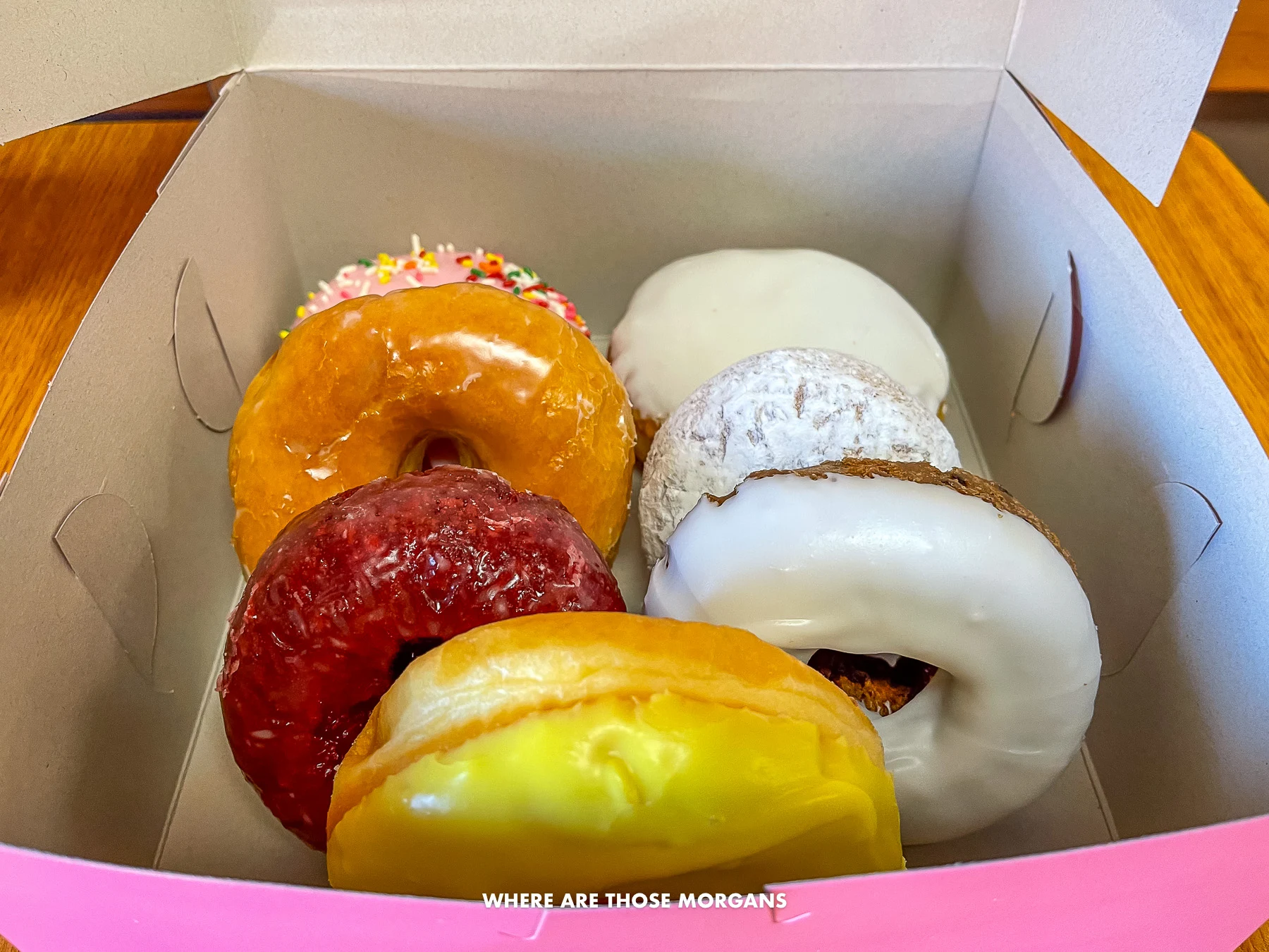 Photo of the inside of a box with 7 donuts of varying colors