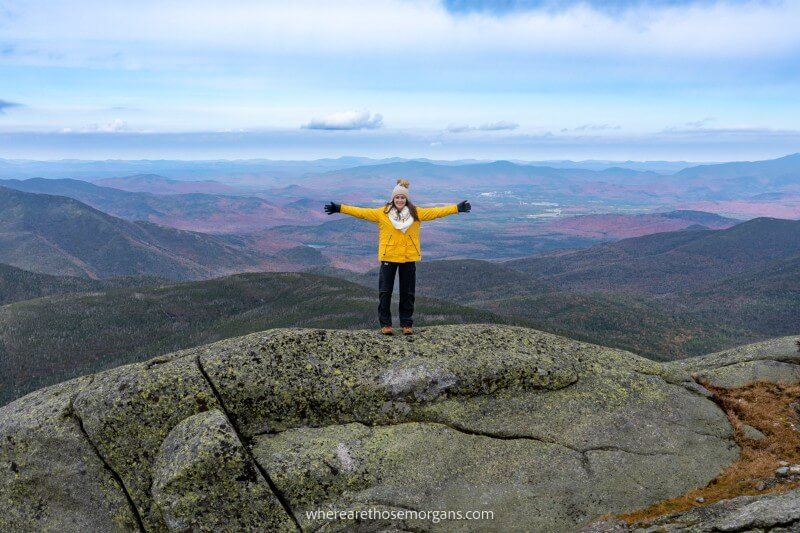 Hiker stood at the top of a mountain peak in New York's Adirondacks with far reaching views