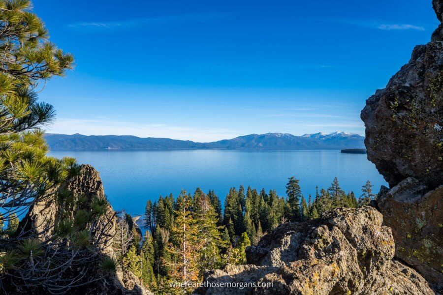 Stunning view over Lake Tahoe blue water and blue sky with rocks in foreground from summit of a short hike one of the most picturesque places to visit in the USA