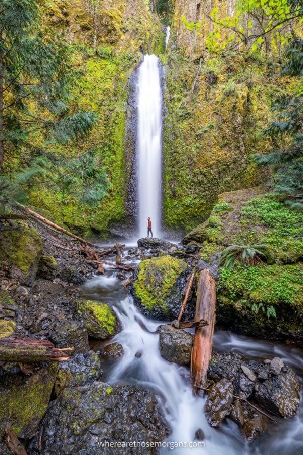 Hiker in middle of thin waterfall along the Columbia River Gorge one of the best US road trips