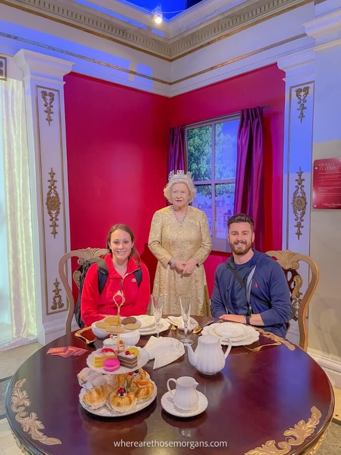 Man and woman sitting with the Queen at Madame Tussauds in New York