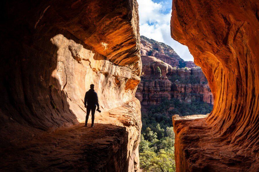 Man with camera in shadow inside Subway Cave sandstone formation in northern Arizona