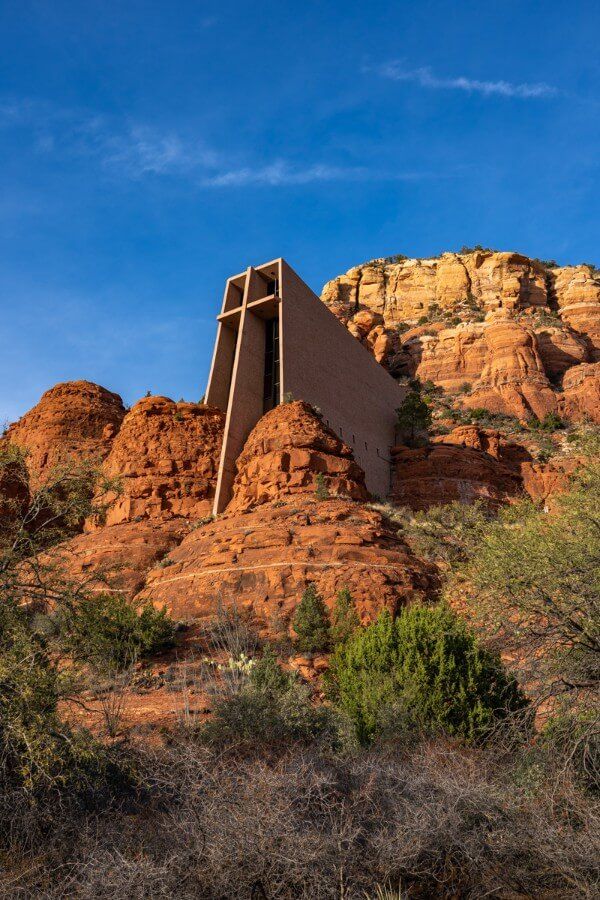 Stunning Chapel of the Holy Cross from below on a slight angle with blue sky and sun lighting up sandstone rocks one of the most popular landmark attractions in sedona az