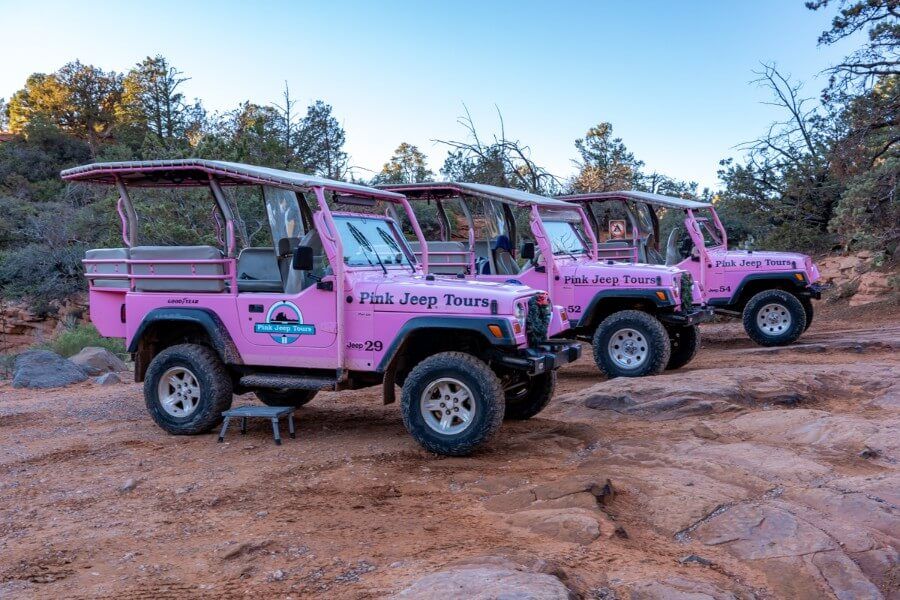 Pink Jeep Tours lined up on a rocky trail at dusk