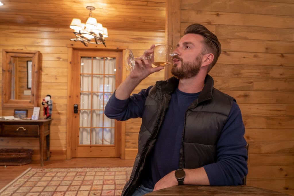 Man drinking wine inside a log cabin style winery in northern arizona