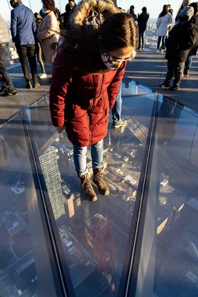 Woman admiring the view through a glass floor 100 stories above Midtown Manhattan