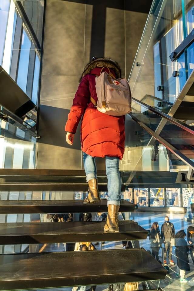 Woman walking up the stairs in a large winter coat