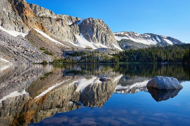 Pristine reflection of rocks in a lake at Medicine Bow Routt